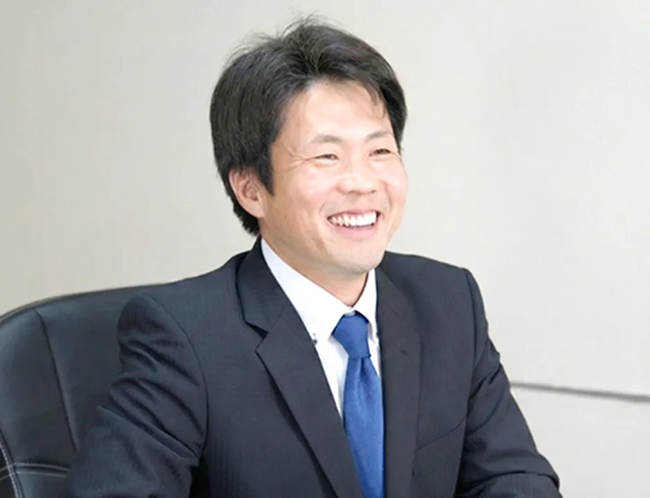 インタビューを受ける株式会社トルクの社員の写真 スーツに青ネクタイで笑顔の男性