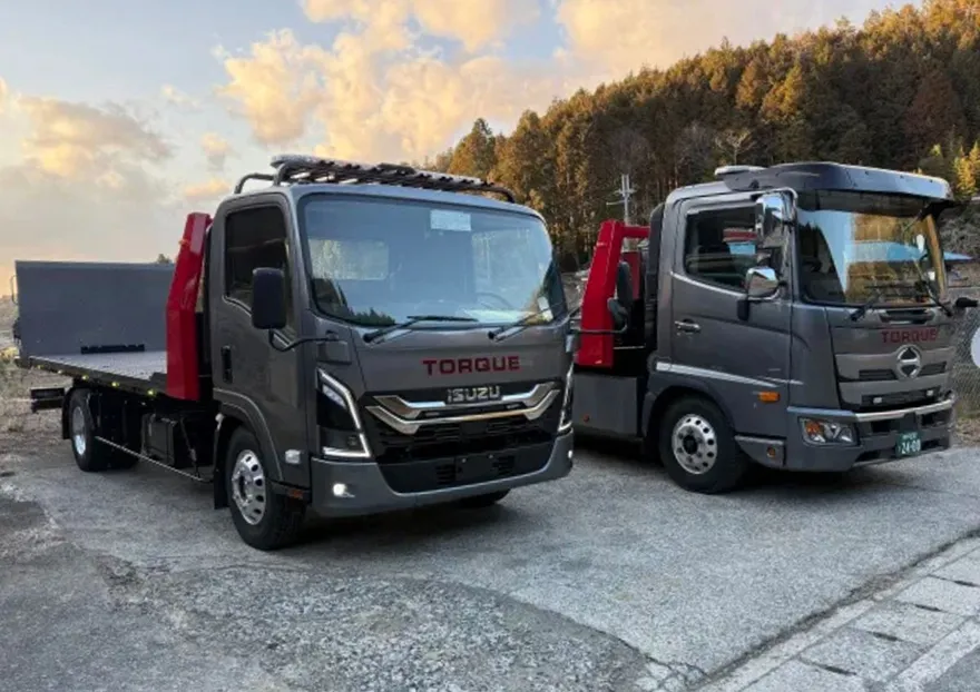 株式会社トルクのレッカー車の写真 グレーの車体に、赤く縁取りされた黒文字でTORQUEと書かれた車が2台並んでいる