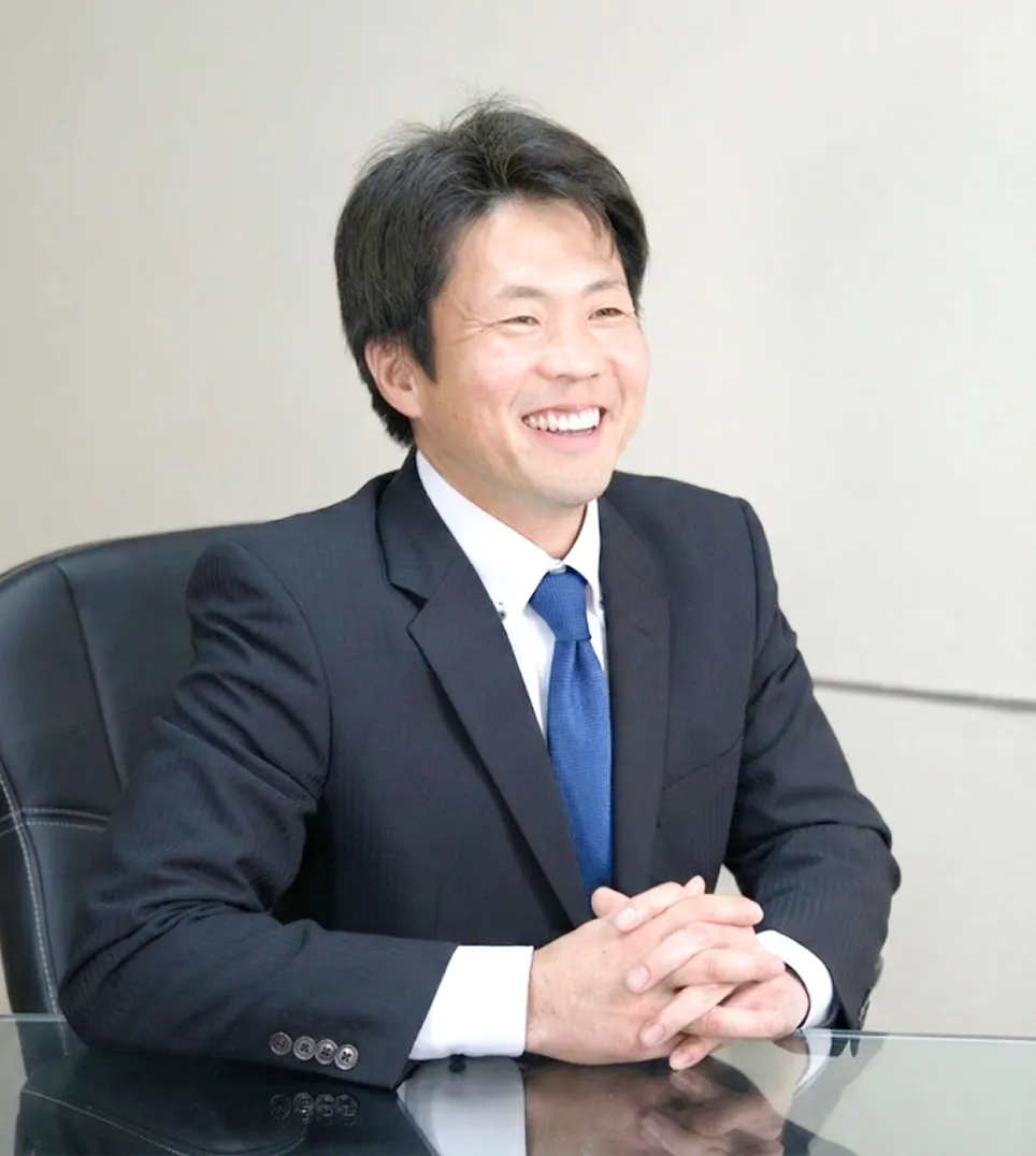 インタビューを受ける株式会社トルクの池上部長の写真 スーツに青ネクタイで笑顔の男性